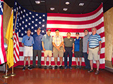 The group poses for a photo at the museum. L-R: Bob Fitzgerald, John Ging, Paul Baker, Jerry Smith, Bob Strand, Wayne Miller, Steve Bisel and Leon Skatburg